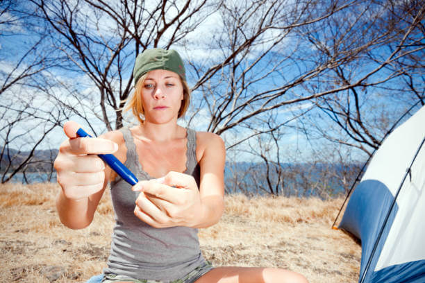 A photograph of a diabetes patient checking her blood sugar level with a meter during a camping trip.