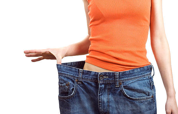 thin female torso wearing a big blue jeans showing difference in weight loss