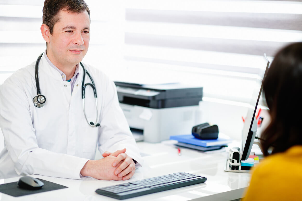 primary care provider looking at patient and listening to her at his desk