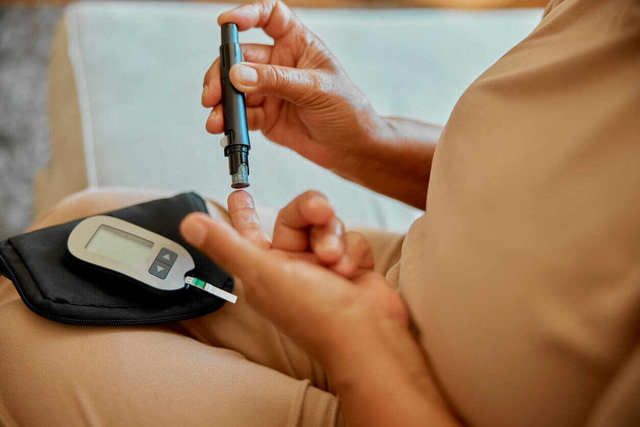 Hands, needle and glucometer for blood test in home with person