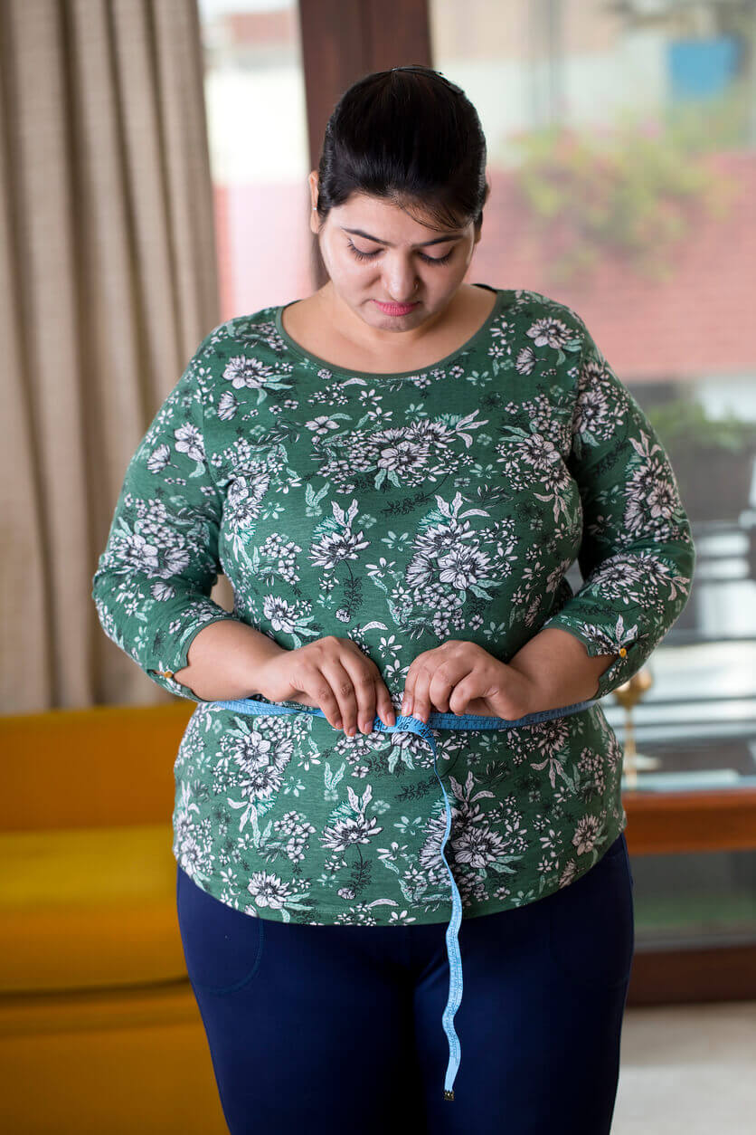 A woman measuring her waist after weight gain from thyroid disease